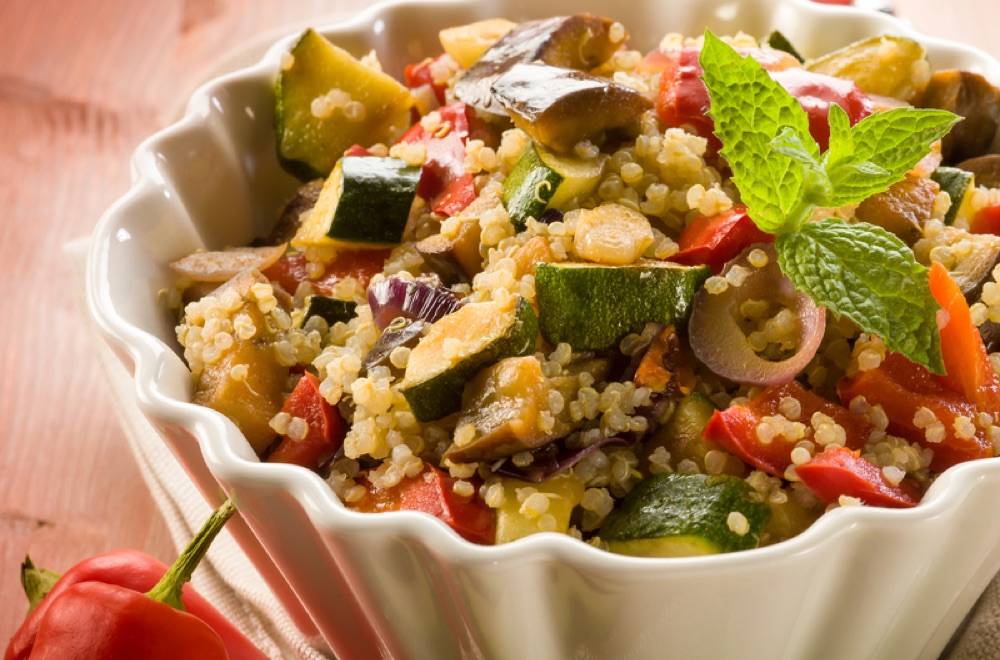 A quinoa grains bowl topped with fresh vegetables.