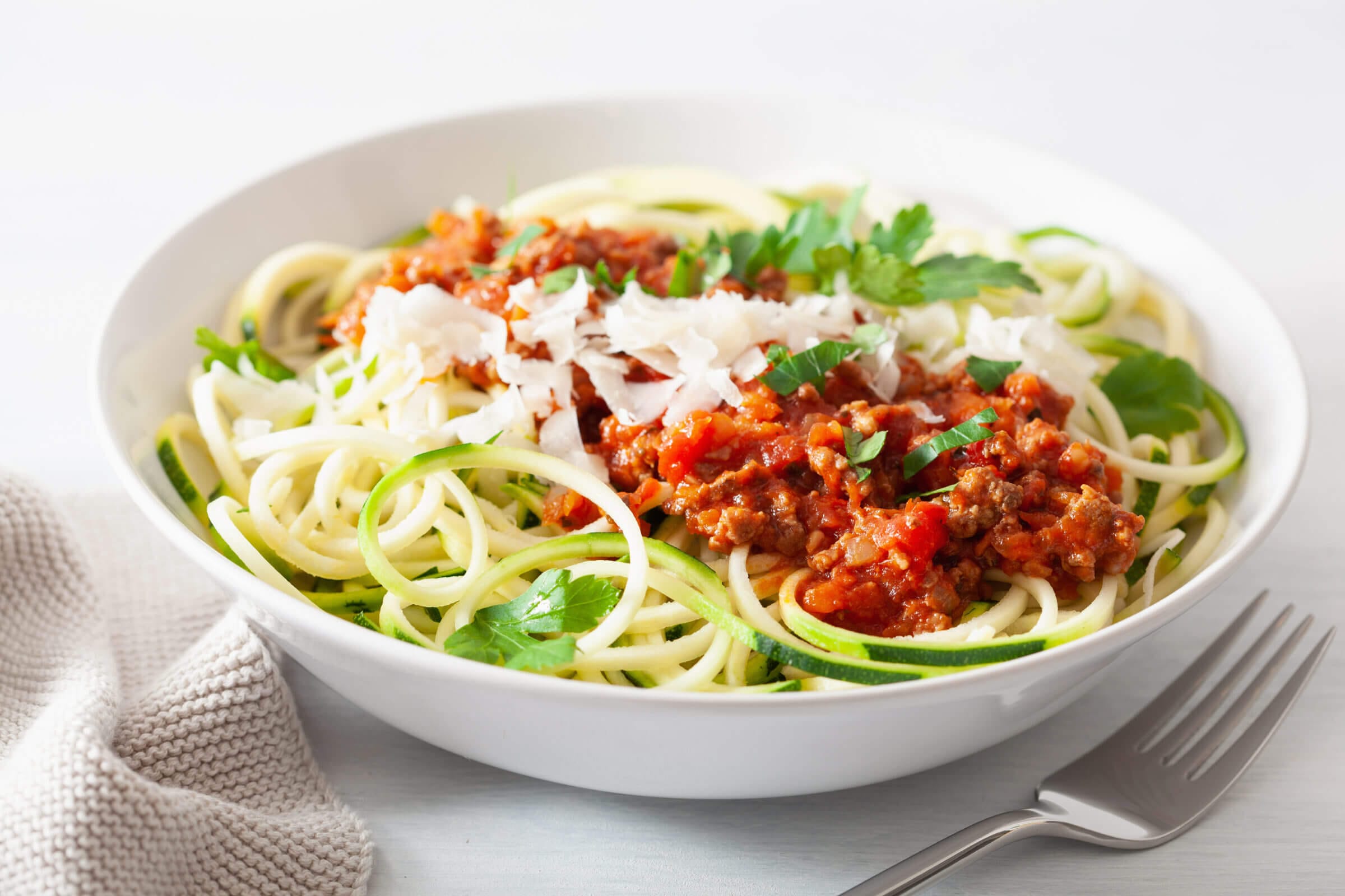 Keto paleo zoodles bolognese: zucchini noodles with meat sauce and parmesan 