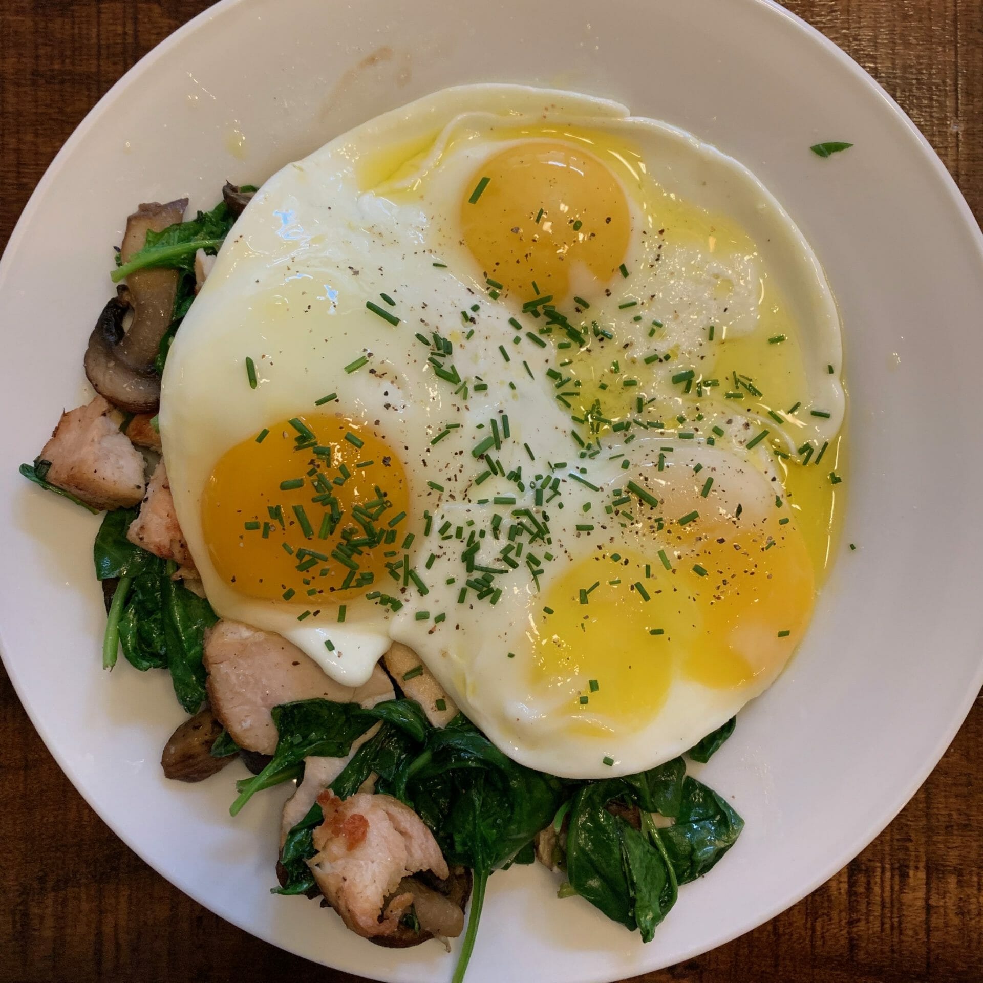 Fried eggs over grilled chicken, spinach and mushrooms