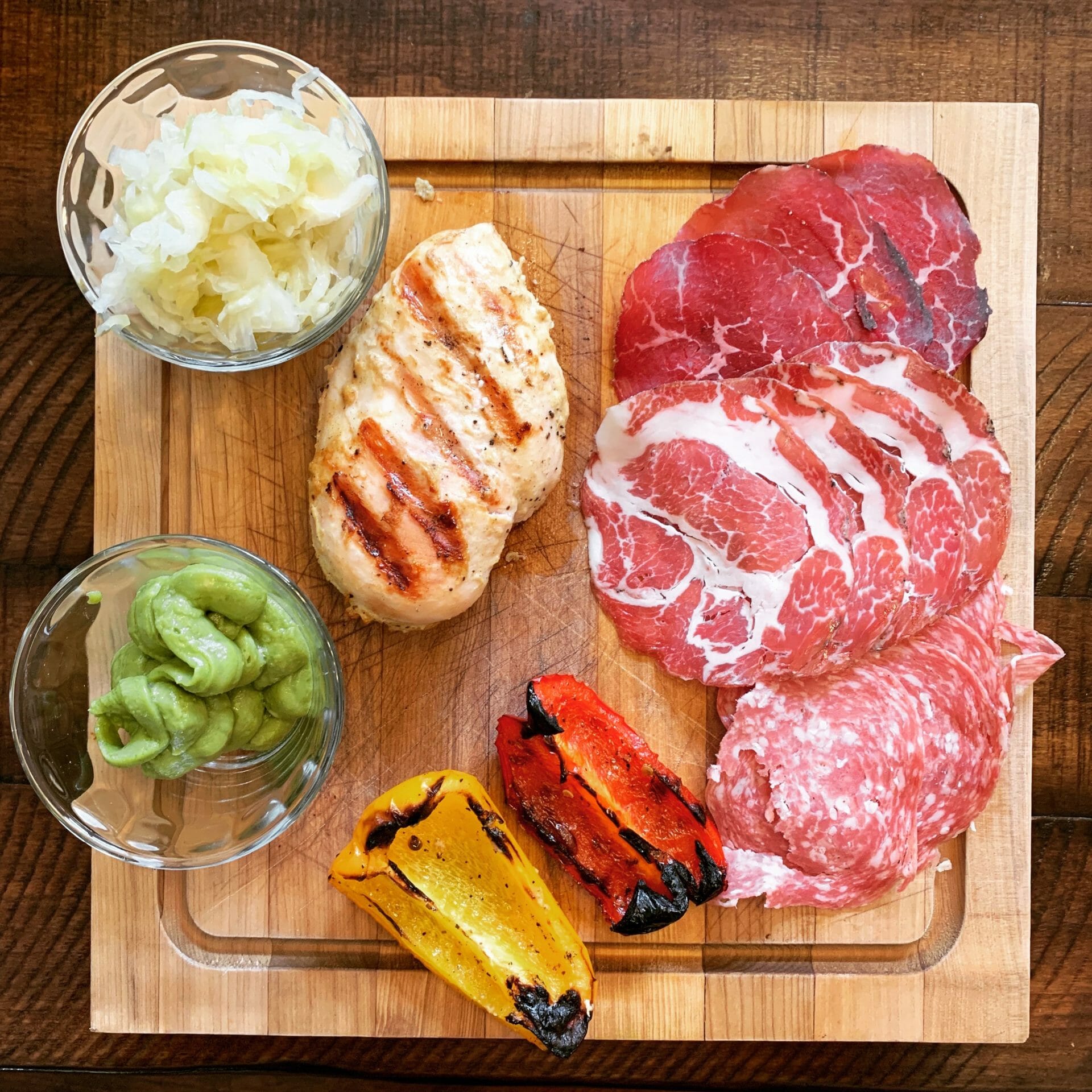 Grilled chicken with uncured cold cuts, sauerkraut, guacamole and grilled peppers