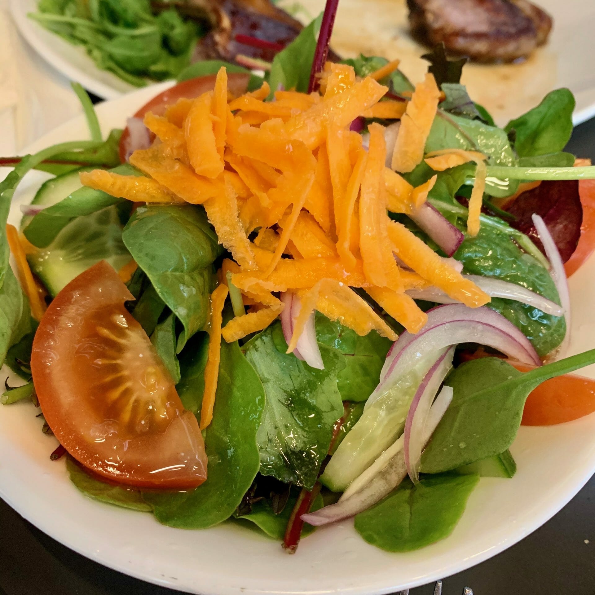 Mixed green salad with carrots, tomatoes, lettuce, cucumbers and onions
