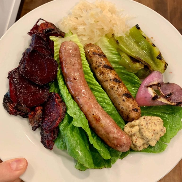 Chicken sausages with baked red beets, lettuce, sauerkraut, grilled peppers and onions