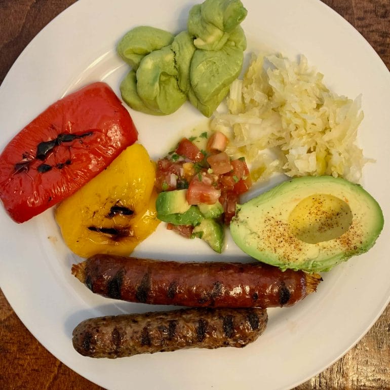 Beef and chicken sausages with grilled peppers, tomato/avocado salad, avocado, guacamole and sauerkraut