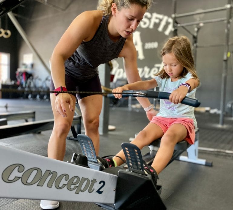 Kathy showing Isabella how to row on Concept2