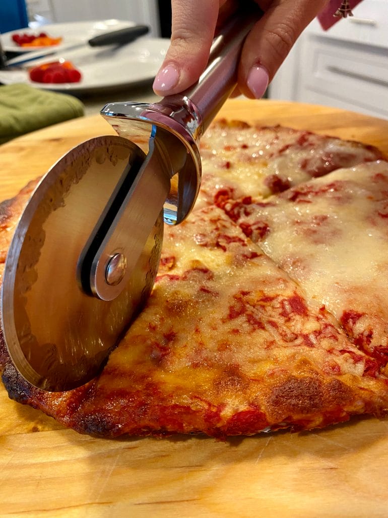 Mi mujer cortando pizza para nuestros hijos