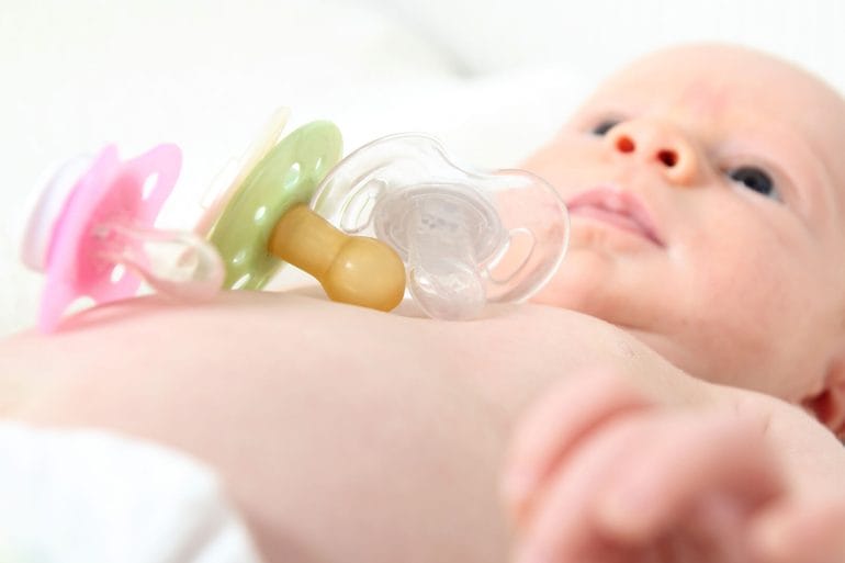 A baby with plastic pacifiers.