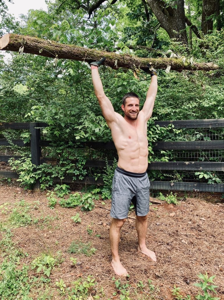 Michael lifting a large log over his head.