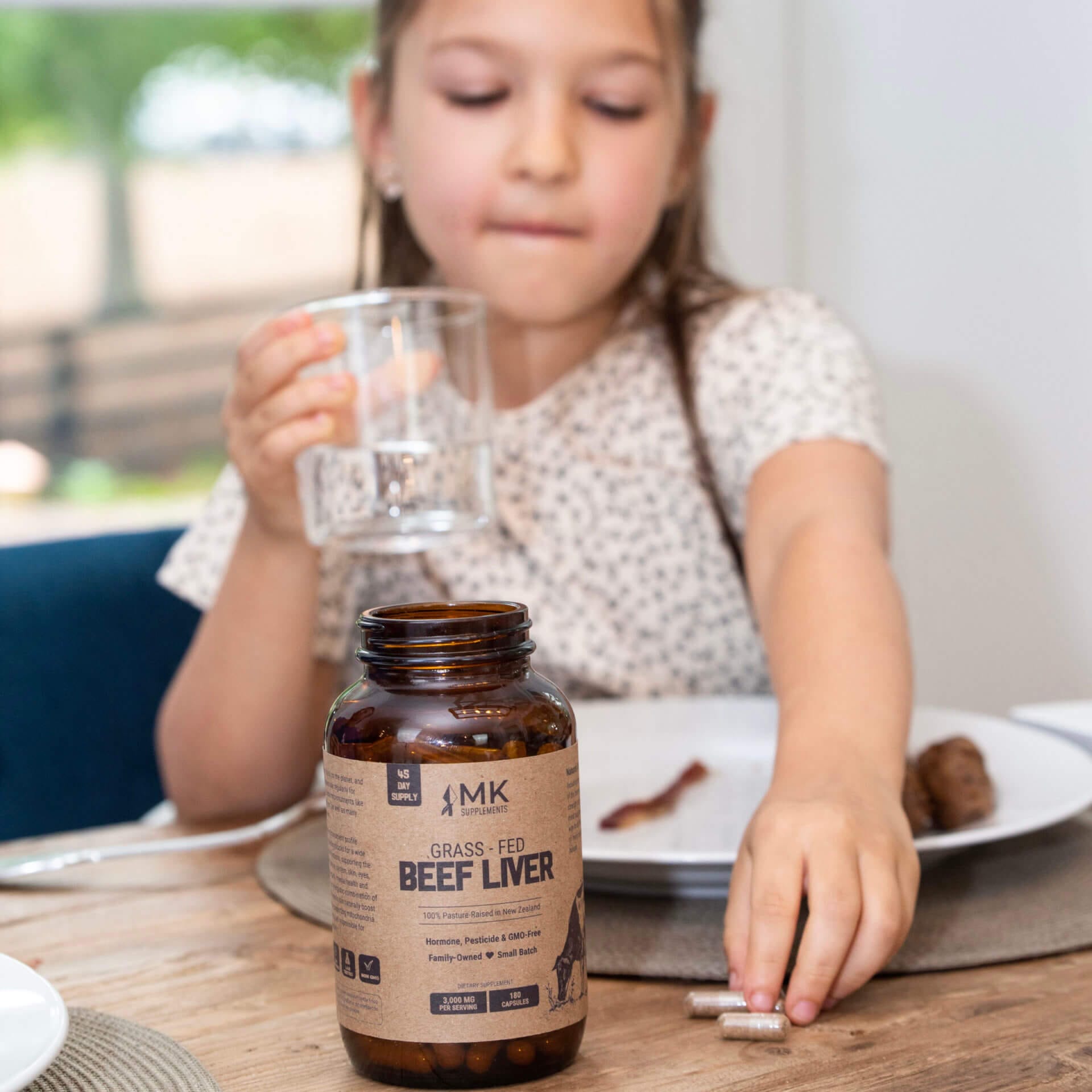 Michael Kummer's daughter Isabella reaching for grass-feed beef liver capsules.