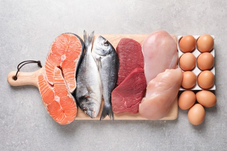 Photo of fish and other meat on a cutting board, with eggs.