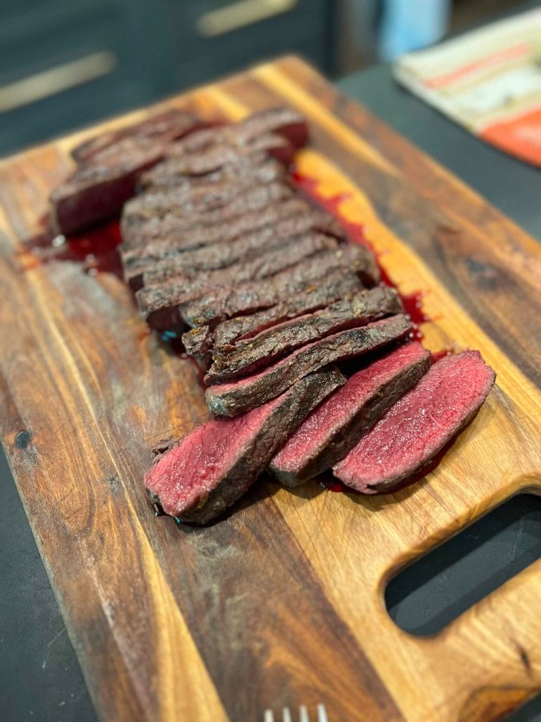 A cutting board with delicious-looking slices of steak.